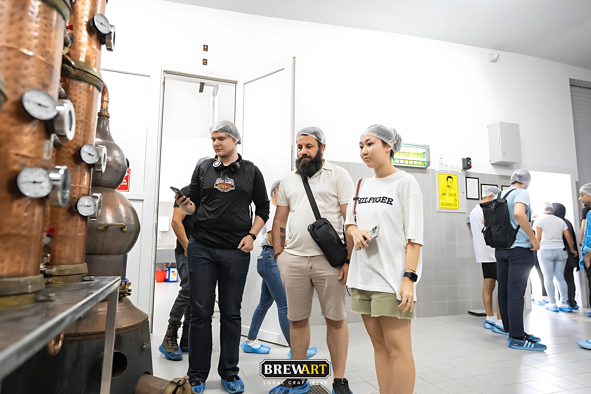 Bakır damıtma imbiği önünde ziyaretçiler